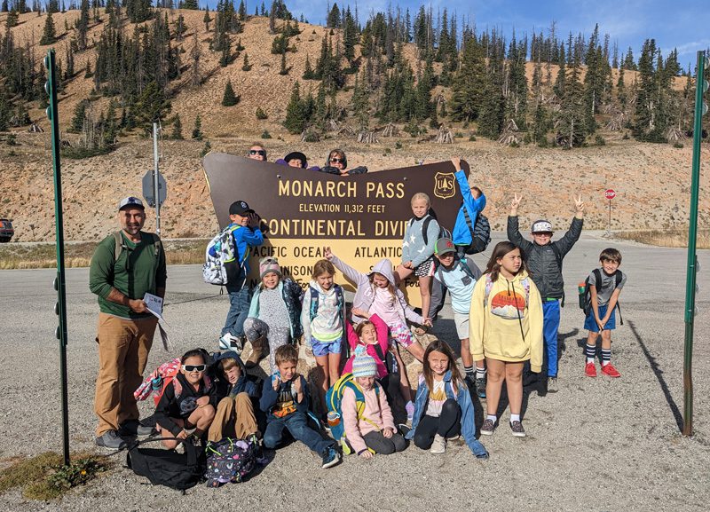 Youth group posing by the Monarch Pass sign at the top of Monarch Pass, Colorado